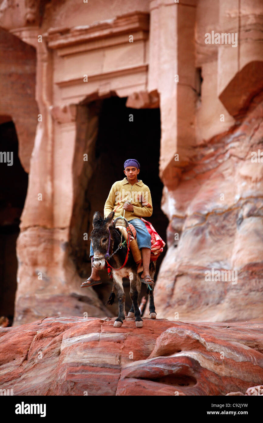 Ritratto di un giovane uomo beduin cavalcando un asino, Petra, Giordania. Foto Stock