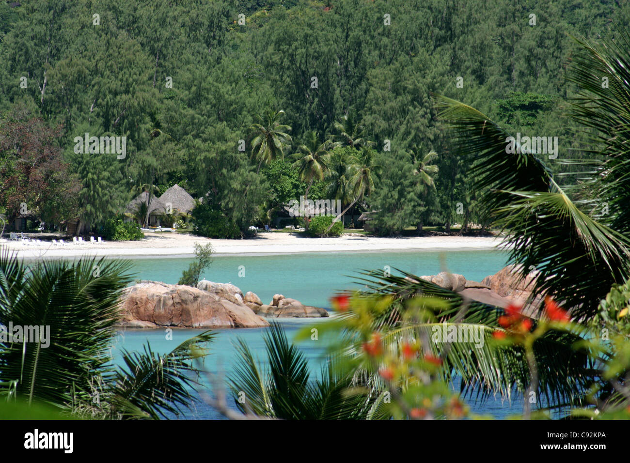 Bay con punta arrotondata mare rocce palme e fitta foresta pluviale sloopes boscoso con tetto in paglia chalet hotel e vacanze Foto Stock