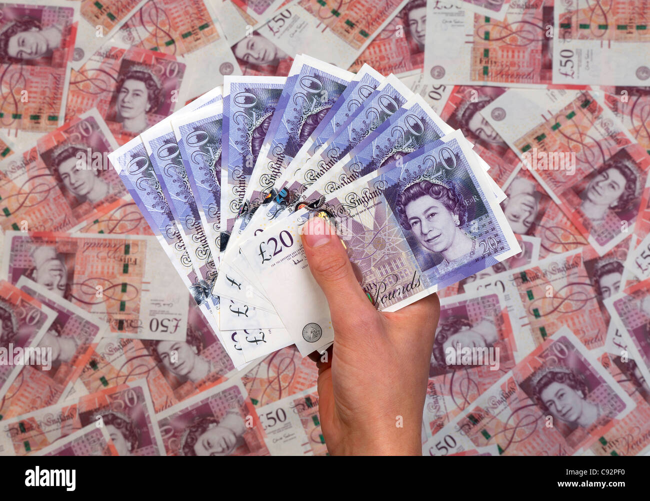 Mano piena di nuovo £20 venti pound note sullo sfondo di £50 cinquanta pound banconote Foto Stock