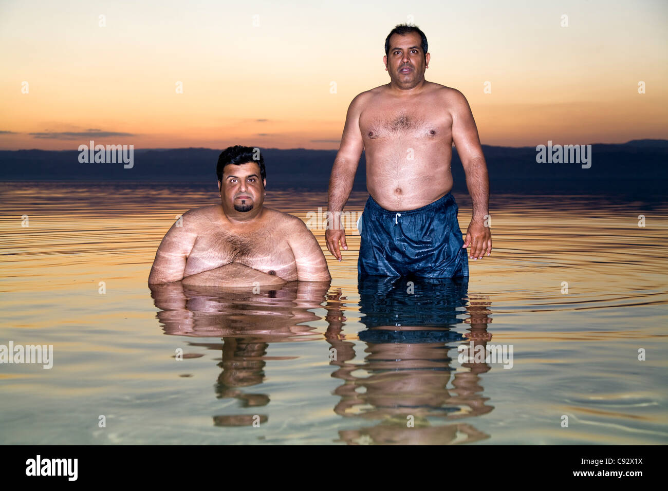 Due uomini giordani / maschio / uomo turistico / turisti relax ad alto contenuto di sale / salato l'acqua salata del Mar Morto lago. Foto Stock