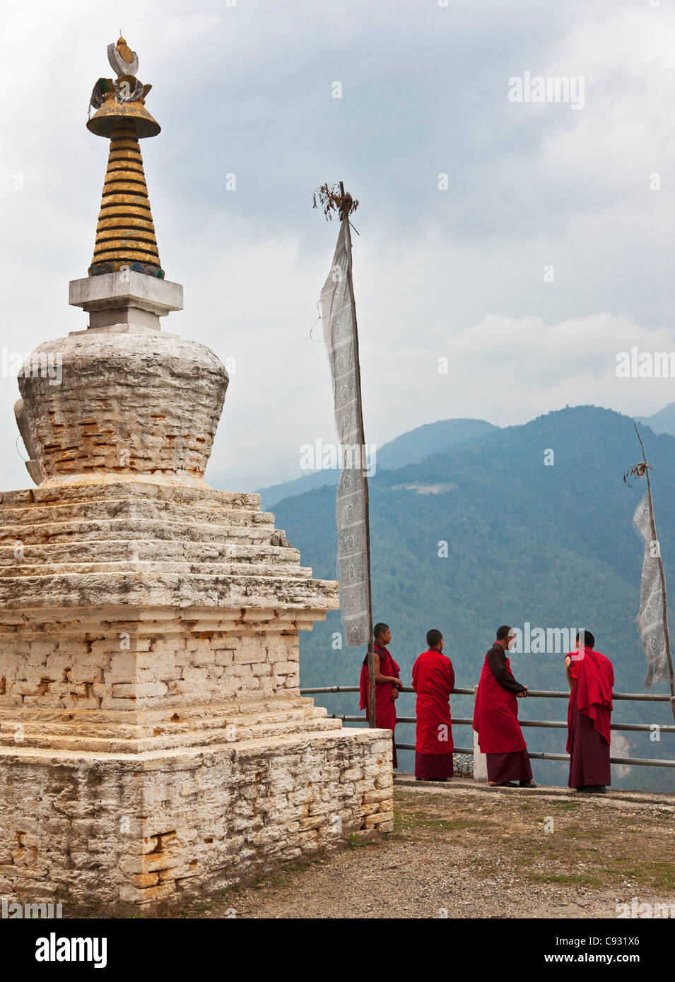 Rosso-derubato monaci rilassarvi accanto ad un chorten o stupa vicino a Mongar. Foto Stock