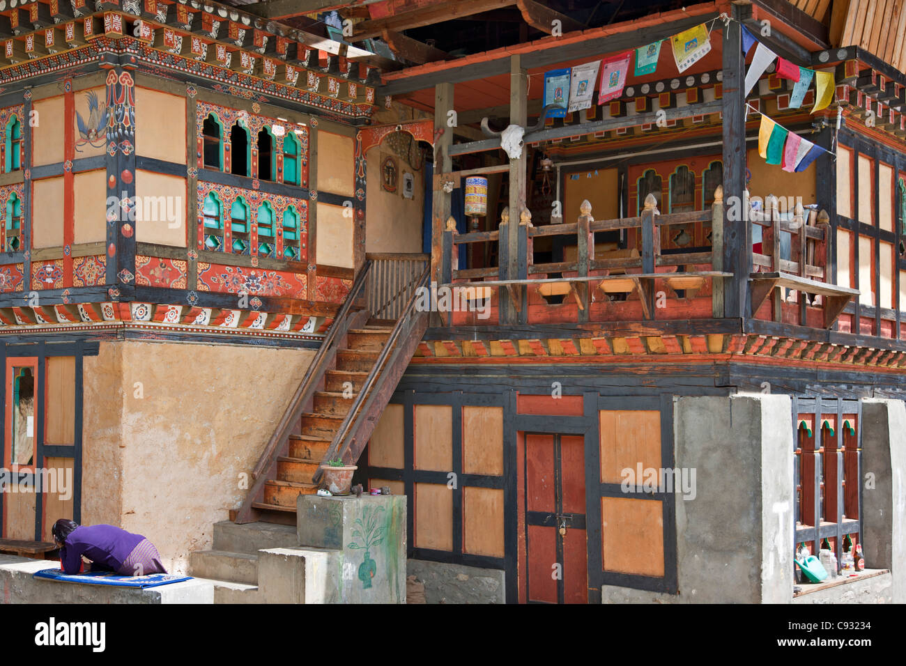 Una tipica casa bhutanesi in Chumey Valley con una ruota di preghiera e la preghiera di bandiere. Foto Stock