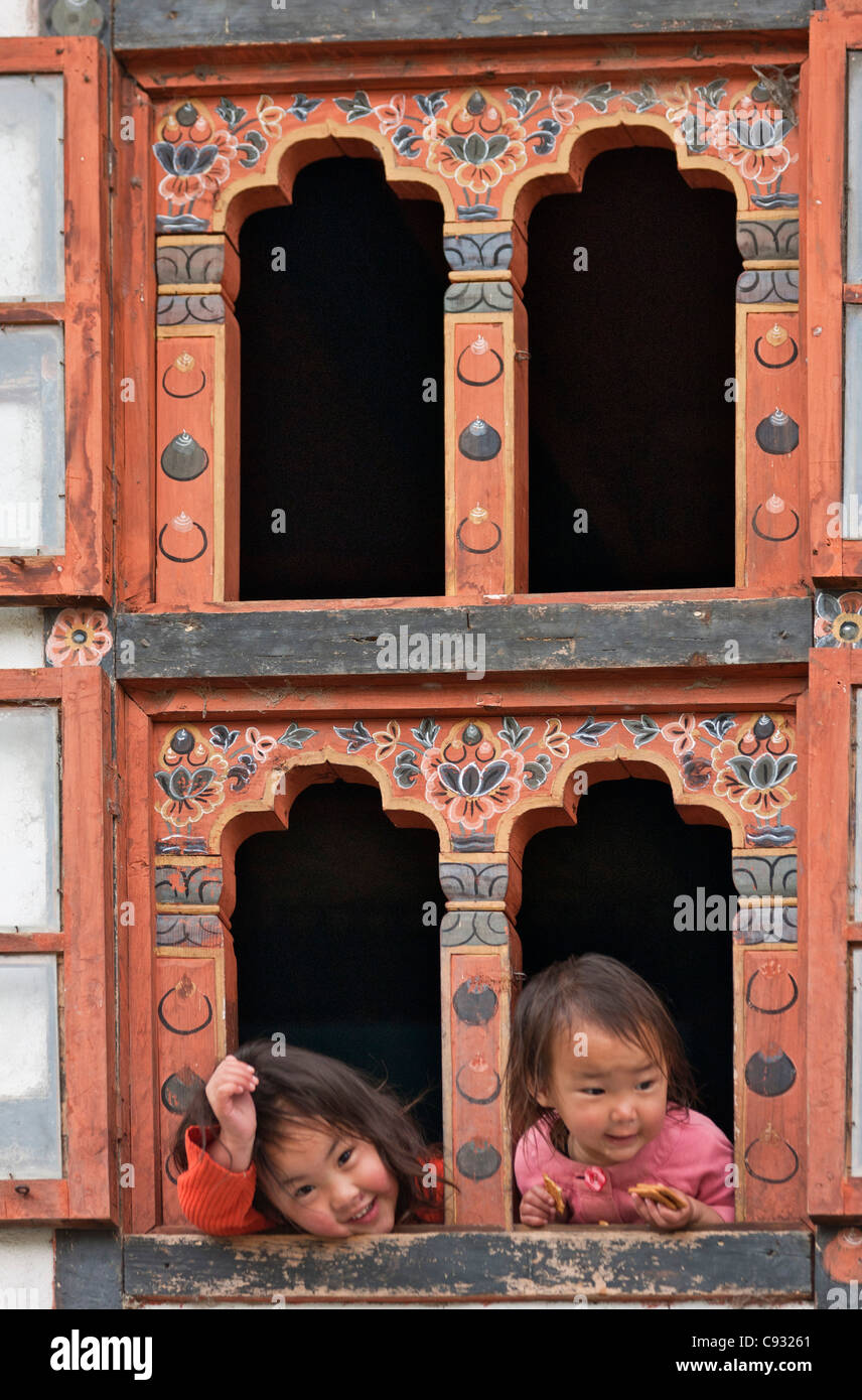 I bambini guardano fuori di una casa tradizionale del Bhutan finestre decorate a Trongsa. Foto Stock