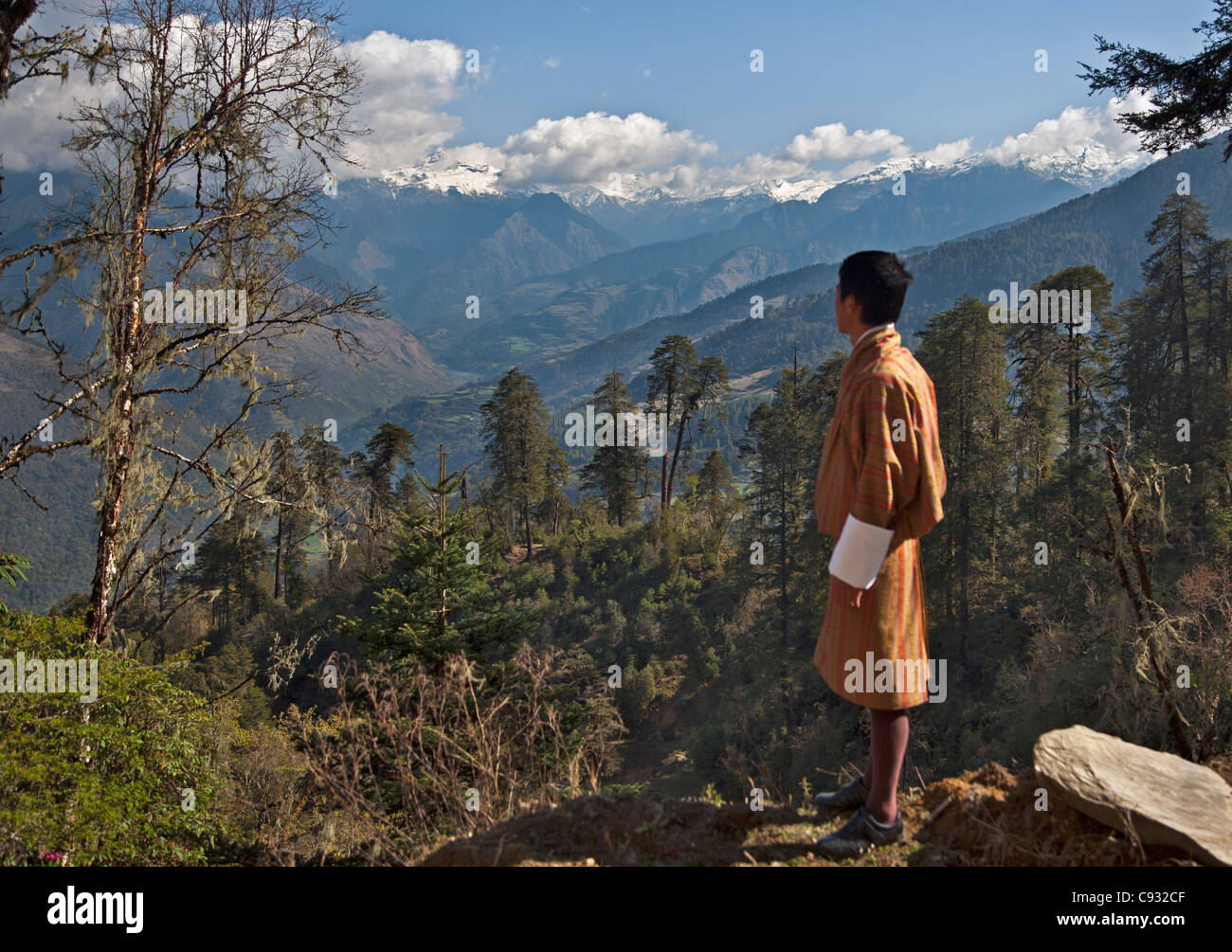 Un uomo bhutanesi in costume opinioni una montagna himalayana dalla Montagna Nera pass noto come Lawa La. Foto Stock