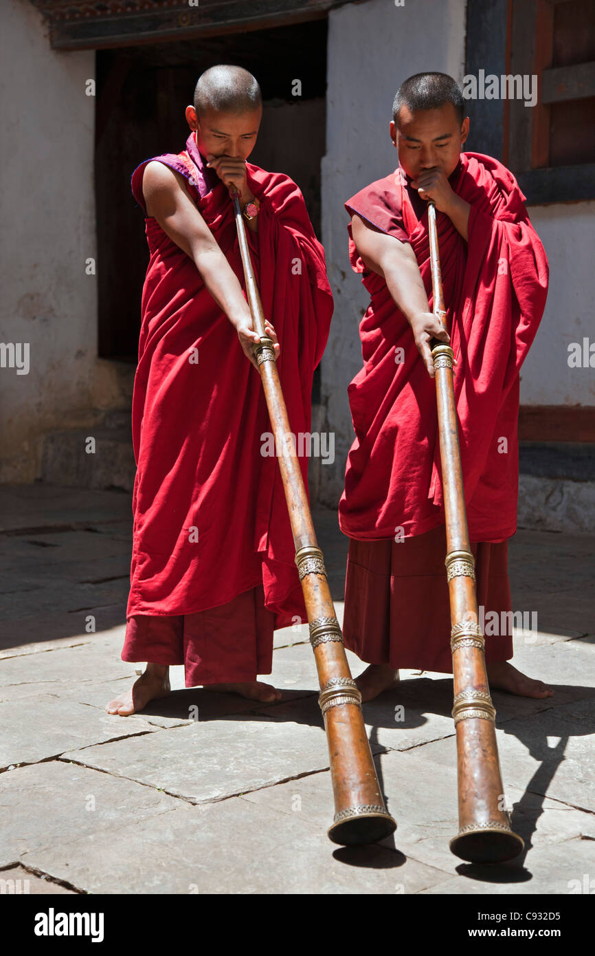 Due monaci soffiare lungo le corna, chiamato dung-chen, in Wangdue Phodrang Dzong (fortezza). Foto Stock