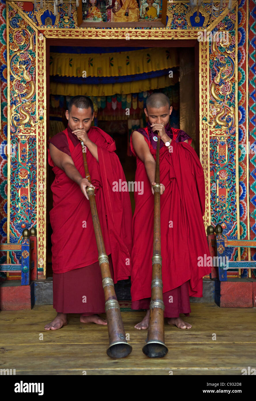 Due monaci soffiare lungo le corna chiamato dung-chen, presso il tempio di Wangdue Phodrang Dzong (fortezza). Foto Stock