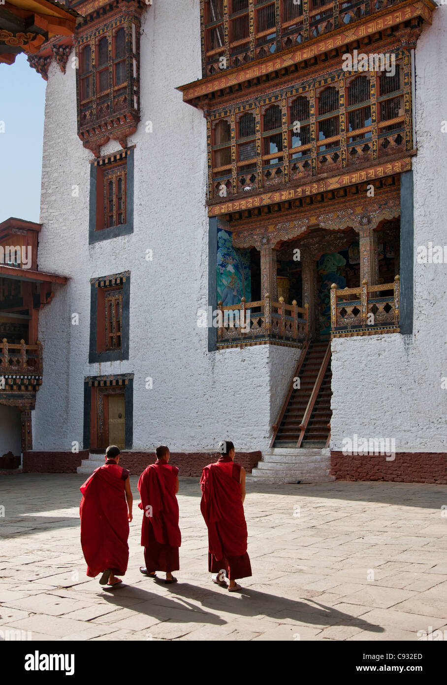 Tre monaci attraversare un cortile in Punakha Dzong, è la seconda più antica e più grande dzong in Bhutan. Foto Stock