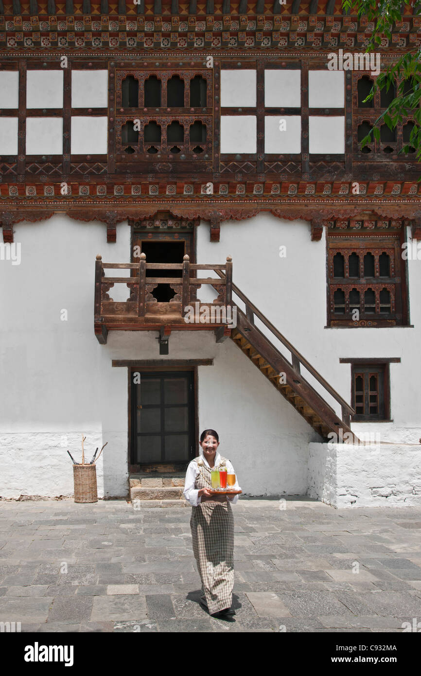 Una cameriera porta i visitatori le loro bevande al Amankora Hotel un gradevolmente ristrutturato la vecchia casa colonica in Punakha Valley. Foto Stock