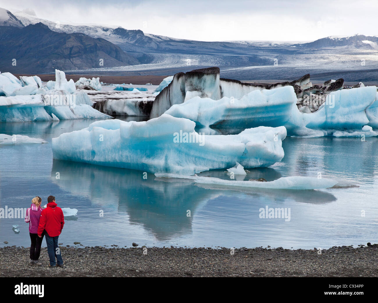 I visitatori a meraviglia i grandi blocchi di ghiaccio galleggiante sulla laguna di Jokulsarlon. Foto Stock