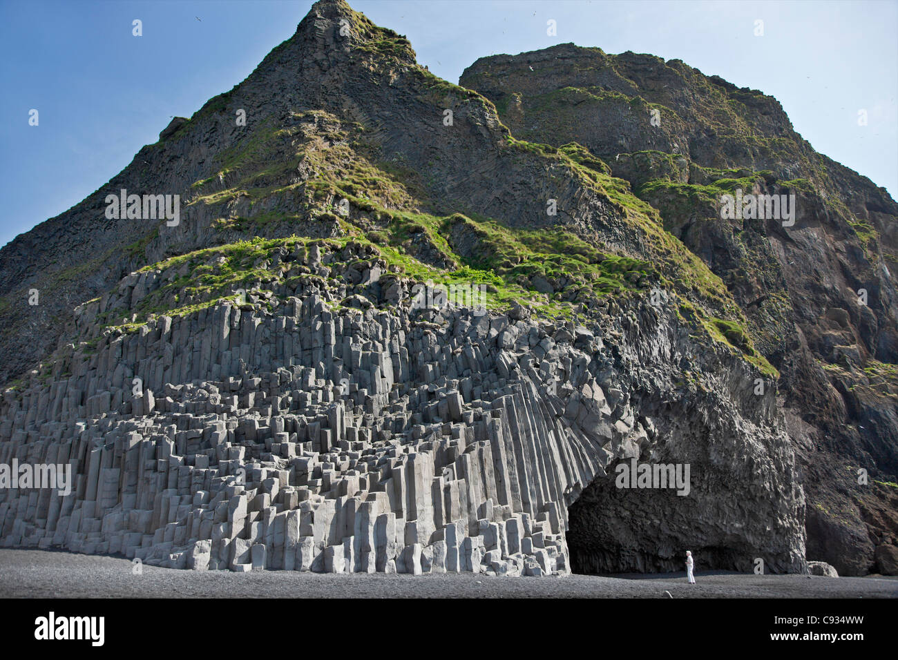 Le enormi colonne di basalto, in piedi come il gigantesco organo a canne e Grotta Garoar dwarf un visitatore di Reynisfjara, a ovest di Vik. Foto Stock