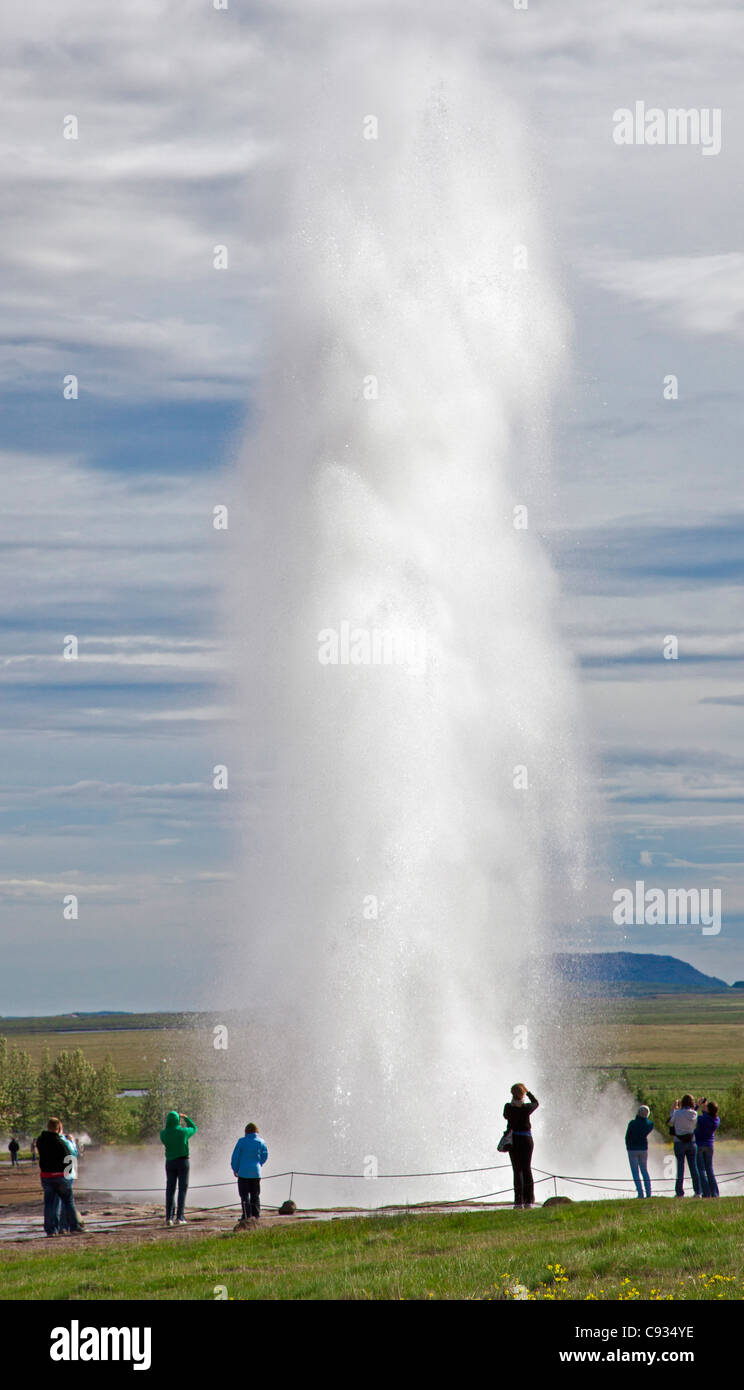 I visitatori a guardare il famoso Strokkur geyser che erutta ogni 8 a 10 minuti. Foto Stock
