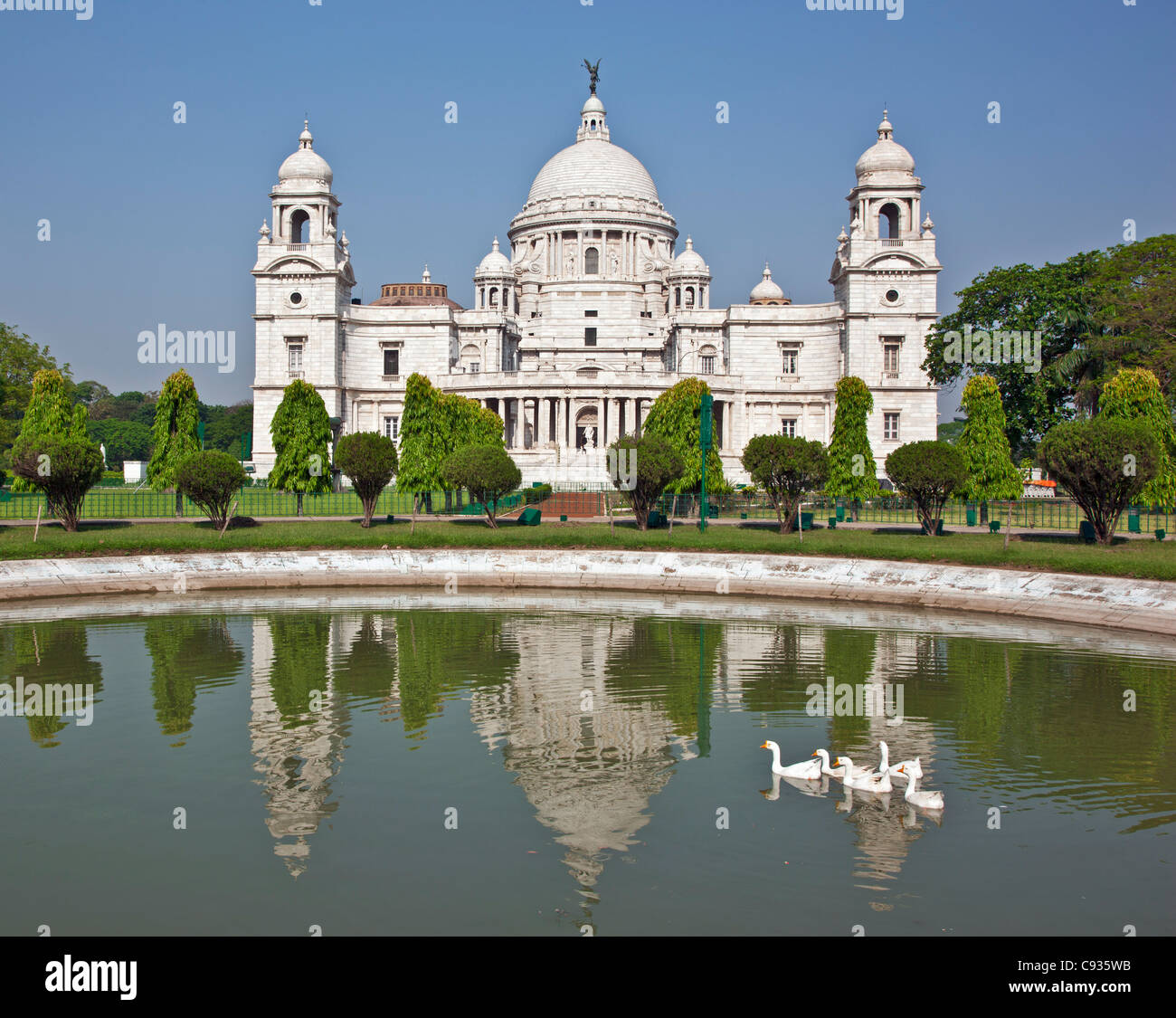 Situato in un rigoglioso parco, il magnifico Victoria Memorial Building con il suo marmo bianco cupole. Foto Stock