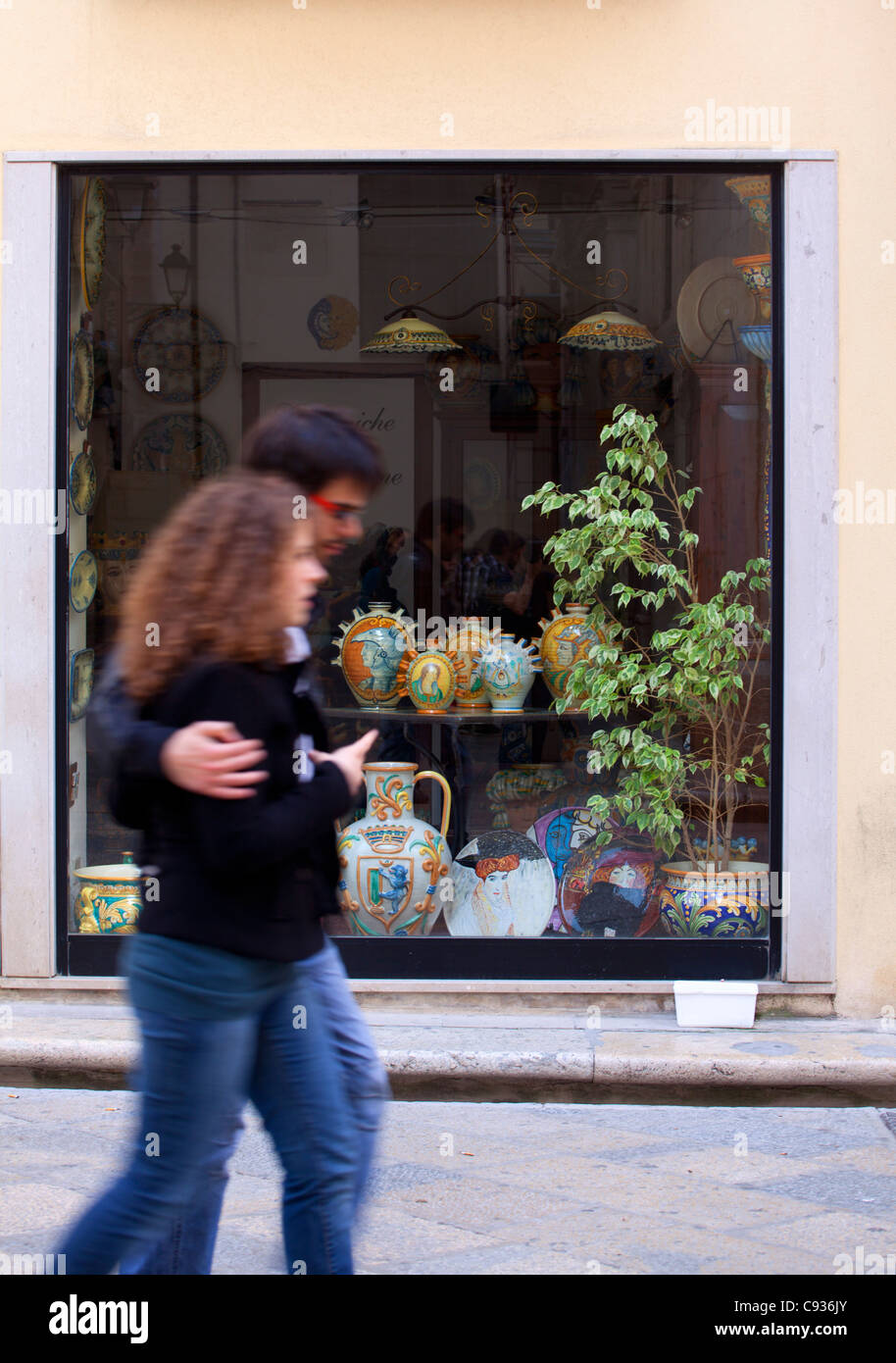 Sicilia, Italia, Europa occidentale; un paio a piedi nella parte anteriore del negozio di vendita di maioliche siciliane vasi in Trapani Foto Stock