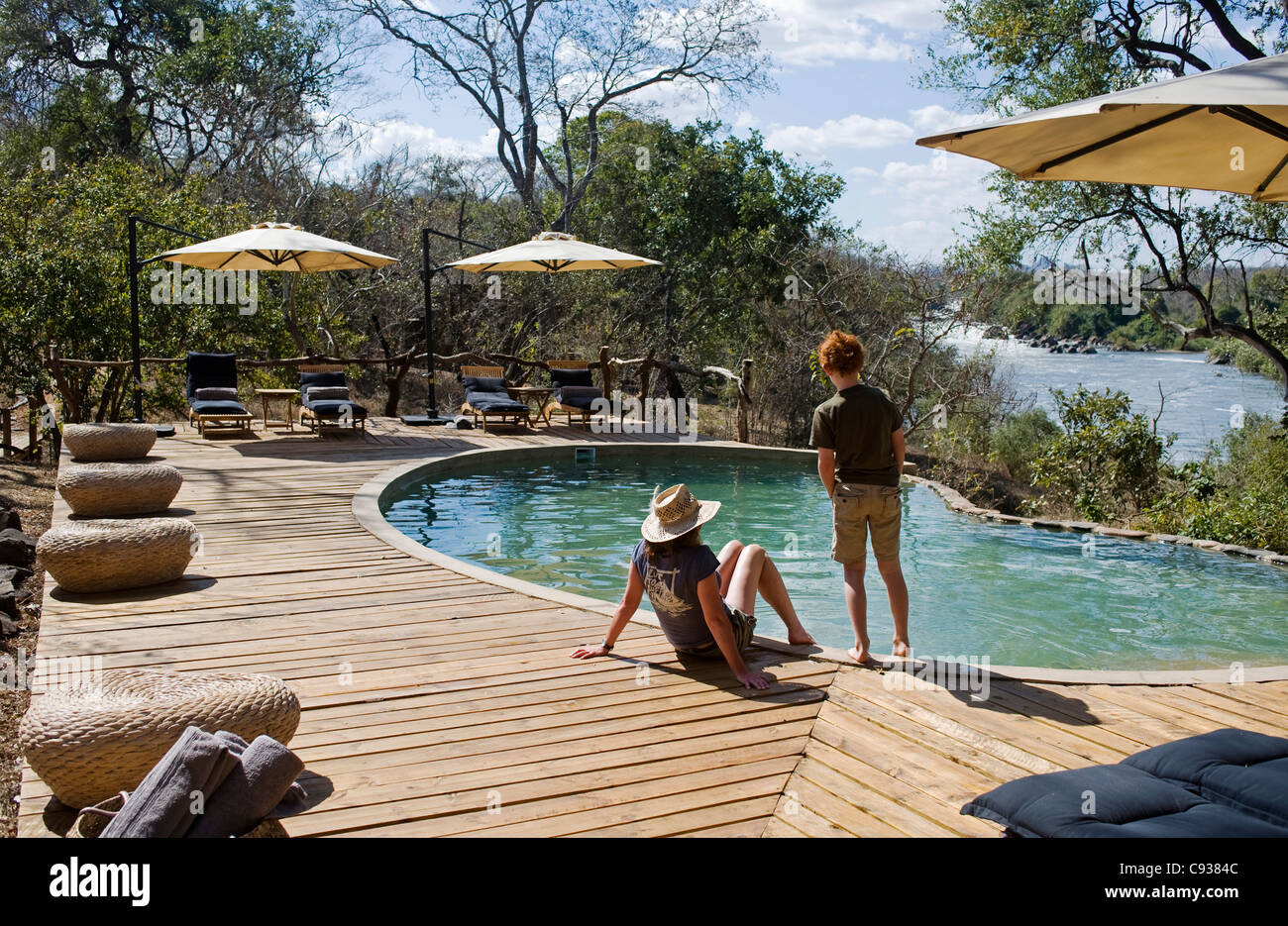 Il Malawi, Majete riserva faunistica. Due visitatori su safari rilassarsi presso la piscina. Signor Foto Stock
