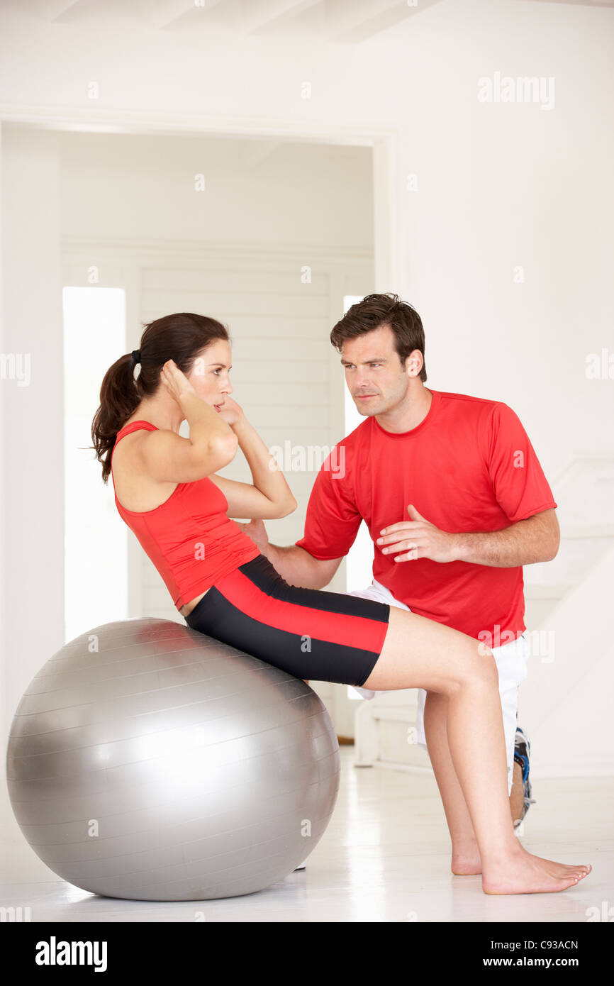 Donna con personal trainer in palestra home Foto Stock