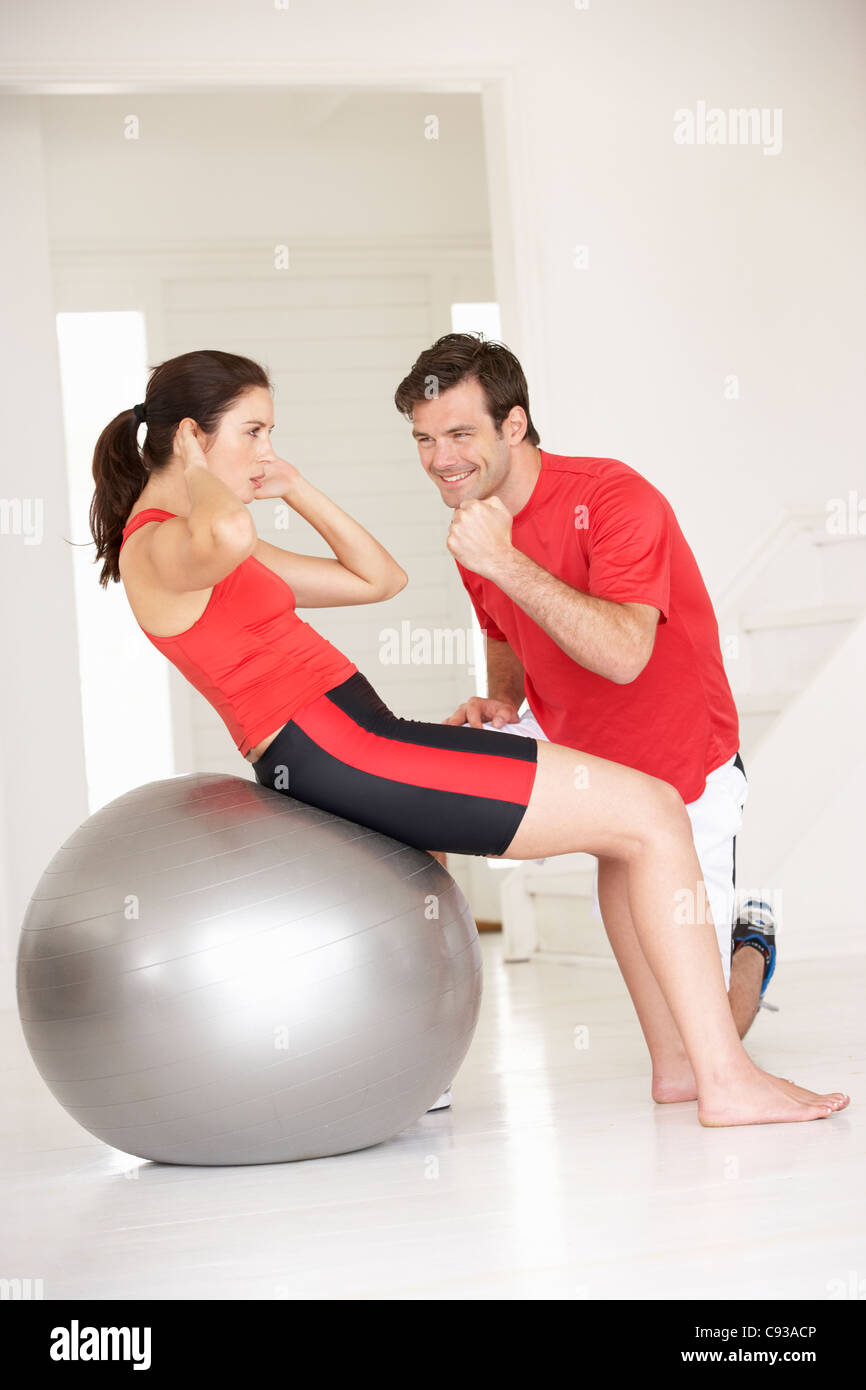 Donna con personal trainer in palestra home Foto Stock