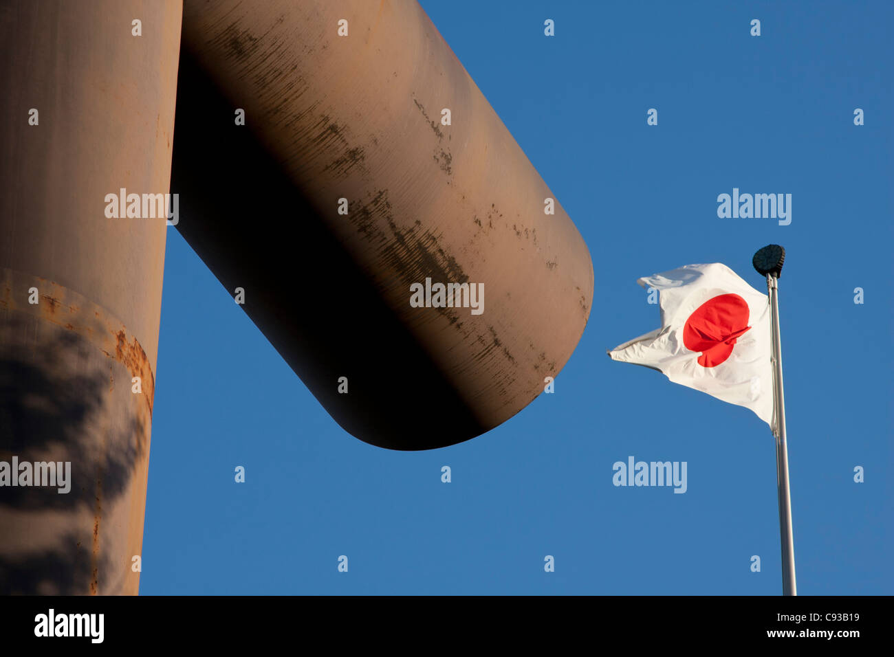 Una bandiera giapponese vola dietro una grande porta di ferro Torii al controverso Santuario Yasukuni di Tokyo, Tokyo, Giappone Foto Stock