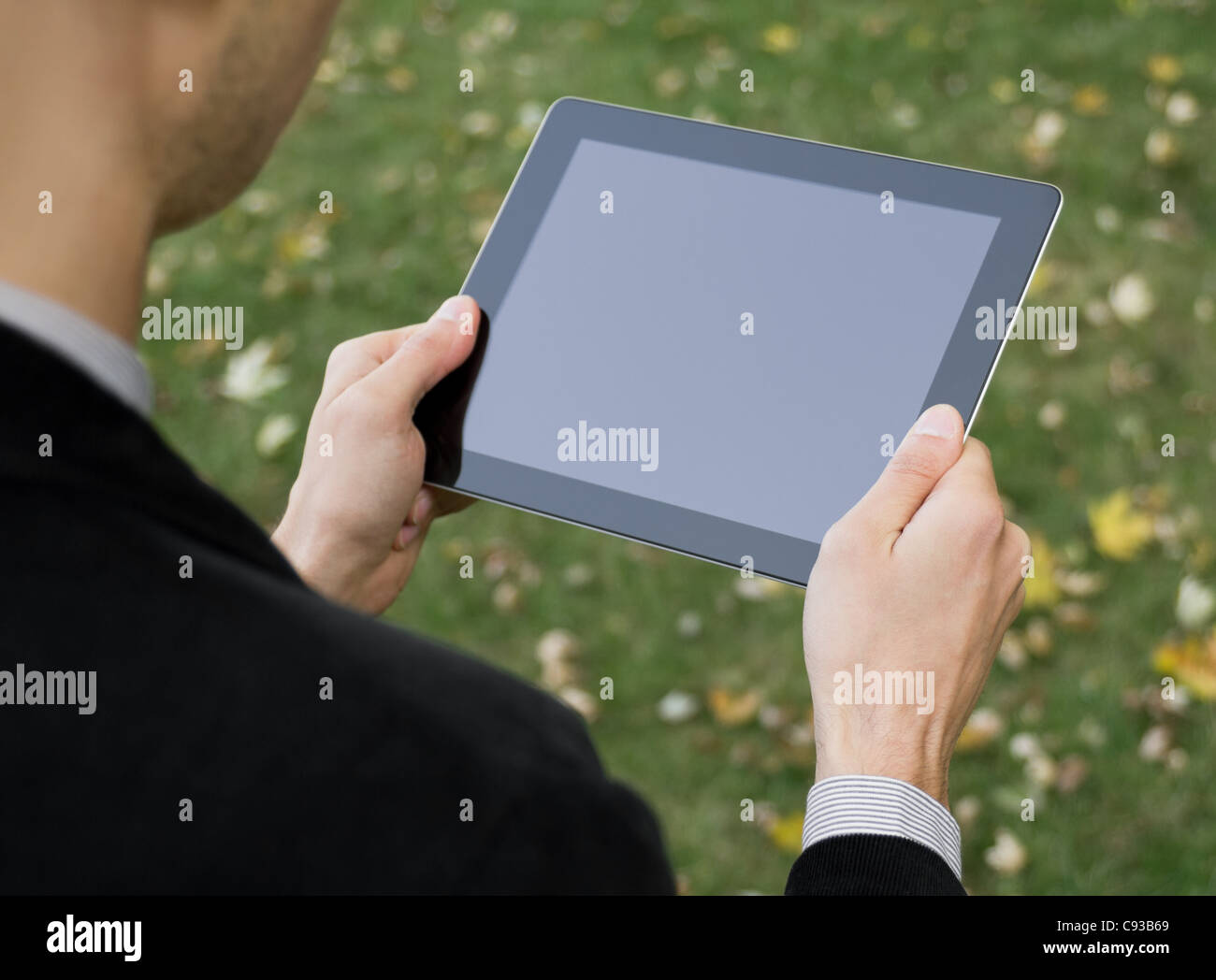 Imprenditore in un parco tenendo un fustellato PC tablet touch-screen. Foto Stock