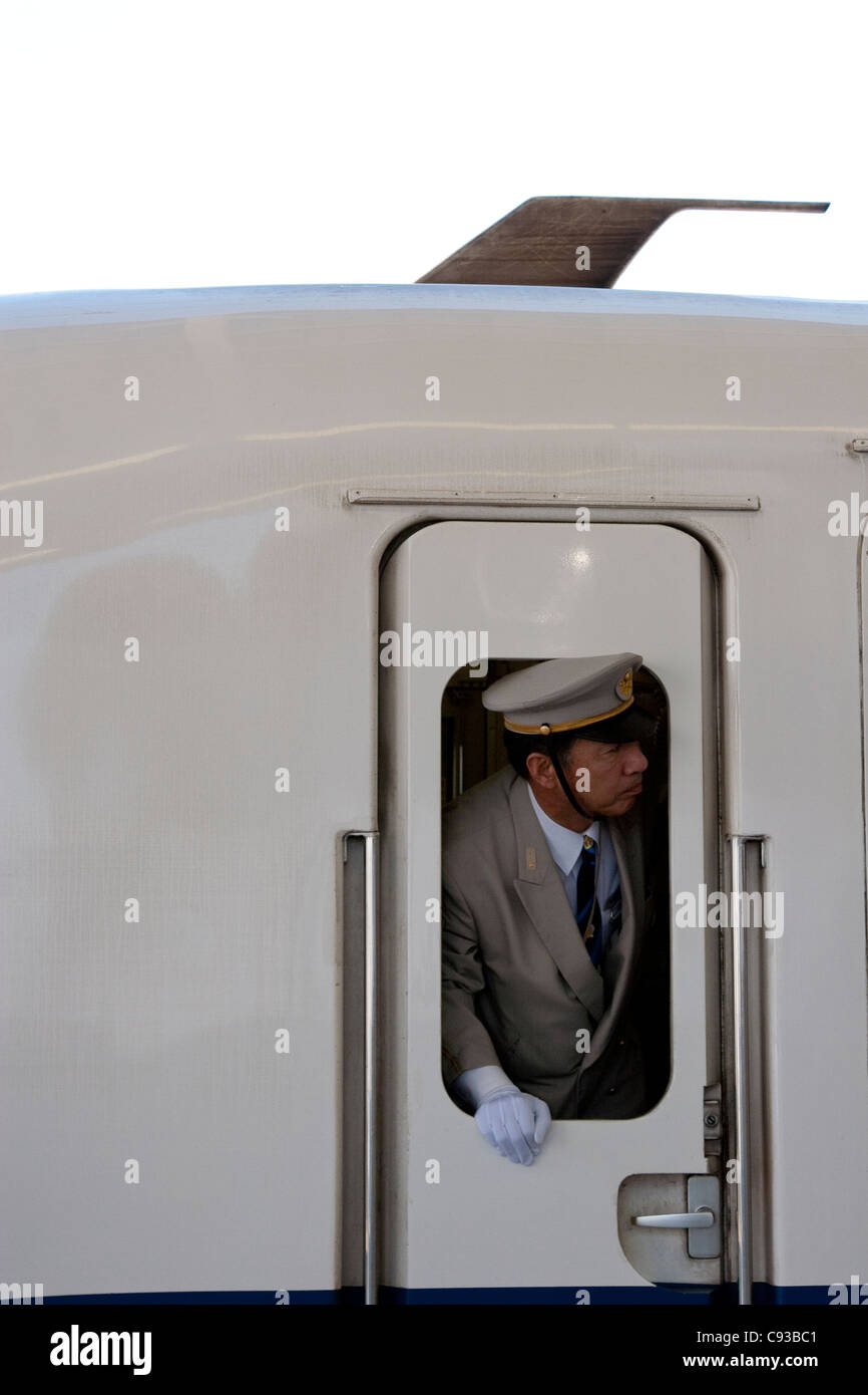 Una guardia del treno si affaccia dalla finestra di uno shinkansen di classe JR 700 (treno superveloce) alla stazione di Shin-Yokohama, Giappone Foto Stock