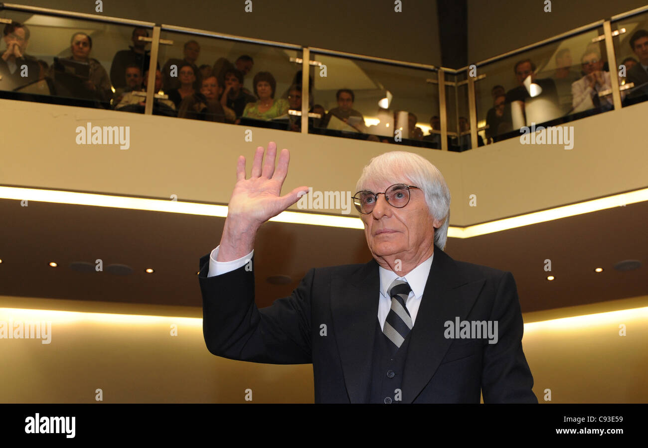 09.11.2011 Monaco di Baviera, Germania. British CEO e presidente di F1's corpo direttivo, Bernie Ecclestone, solleva la sua mano al tribunale dove un'altra sessione del processo contro un ex capo della gestione del rischio in banca bavarese BayernLB era che si terrà presso la corte distrettuale di Monaco di Baviera, Germania, 9 novembre Foto Stock