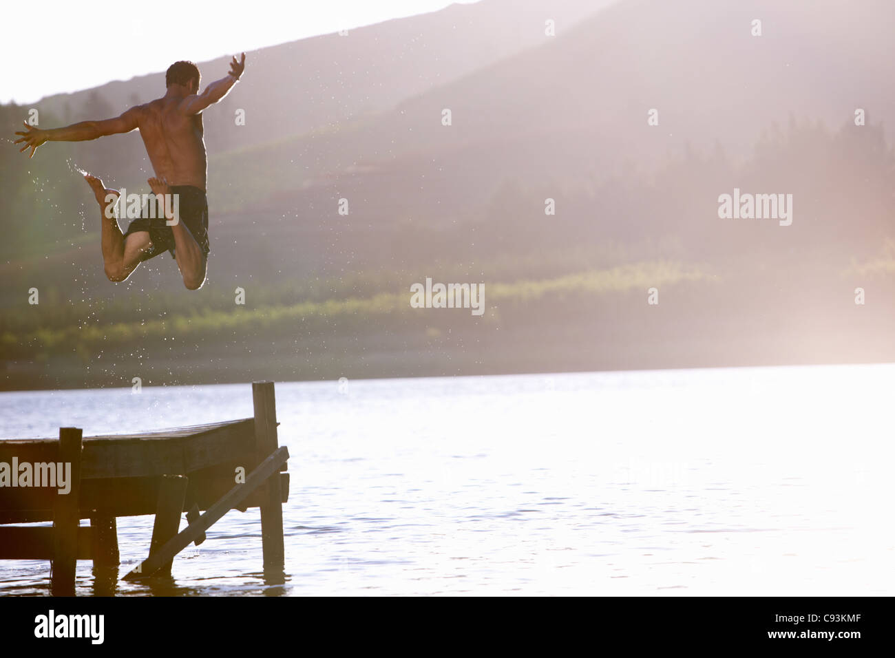 Giovane uomo saltando nel lago Foto Stock