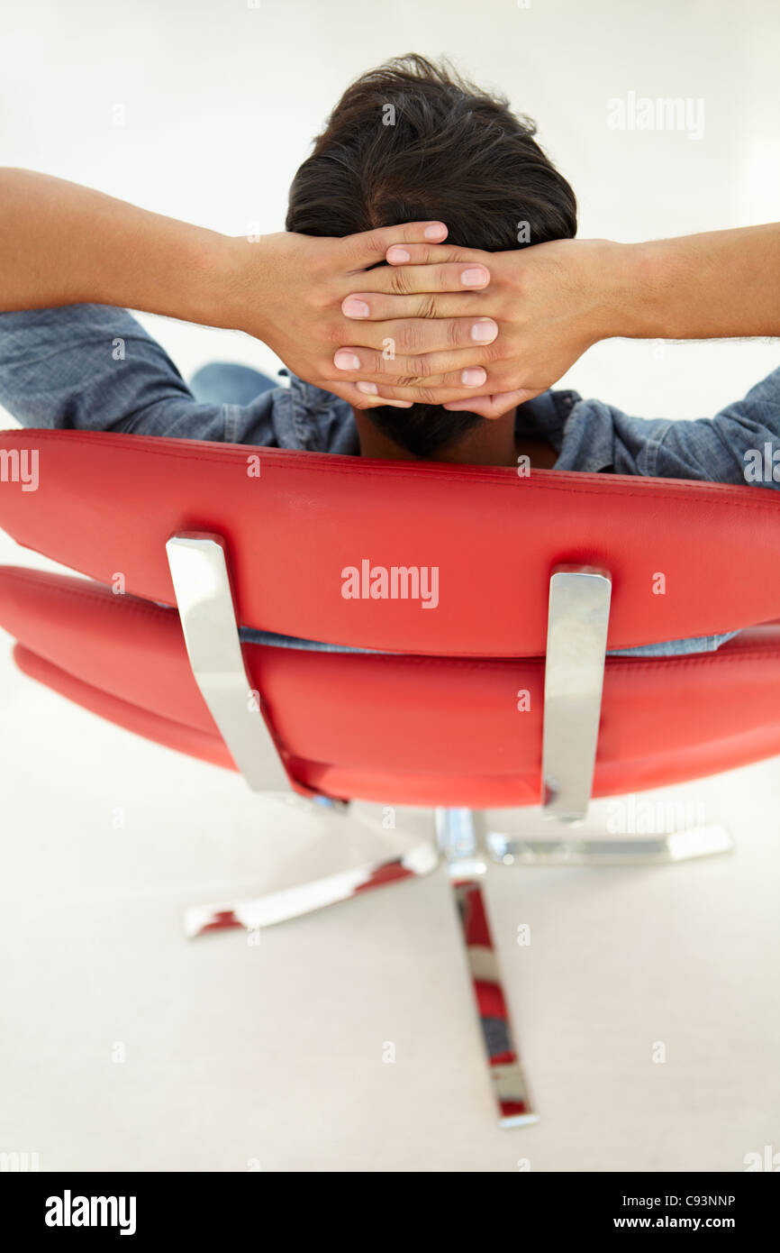 Giovane uomo rilassante in sedia rossa Foto Stock