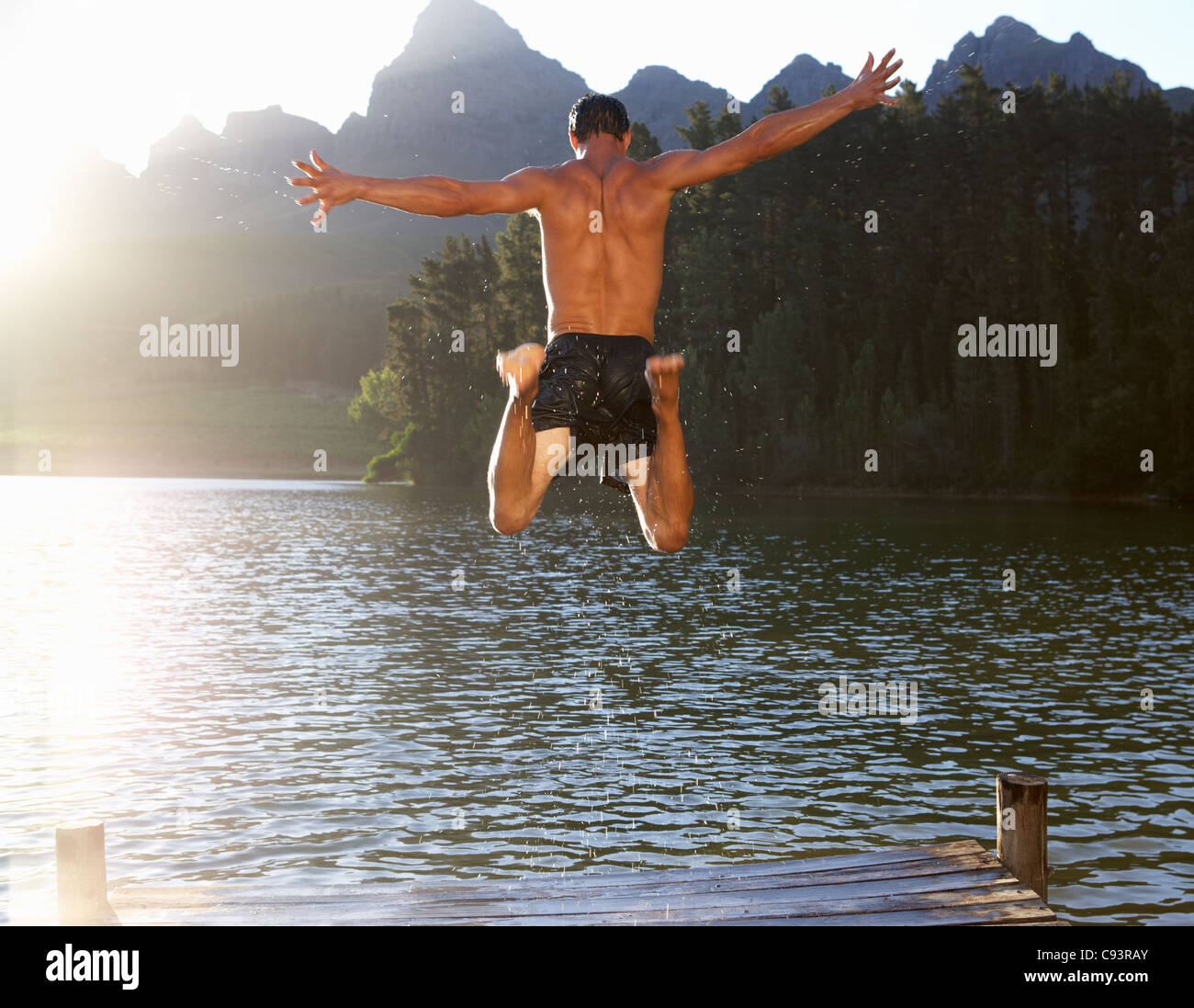 Giovane uomo saltando nel lago Foto Stock
