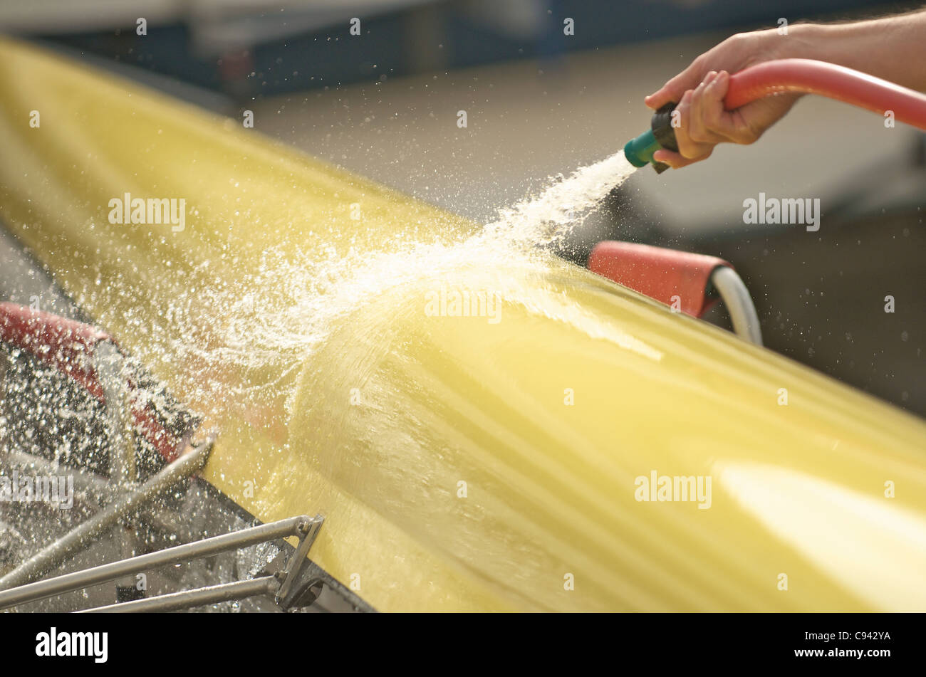 Un vogatore lavando il suo doppio scull canotto. Foto Stock