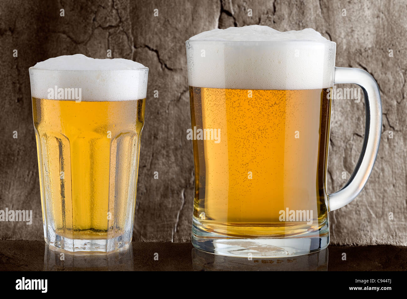 Due bicchieri di birra Pilsner contro un sfondo stoney Foto Stock