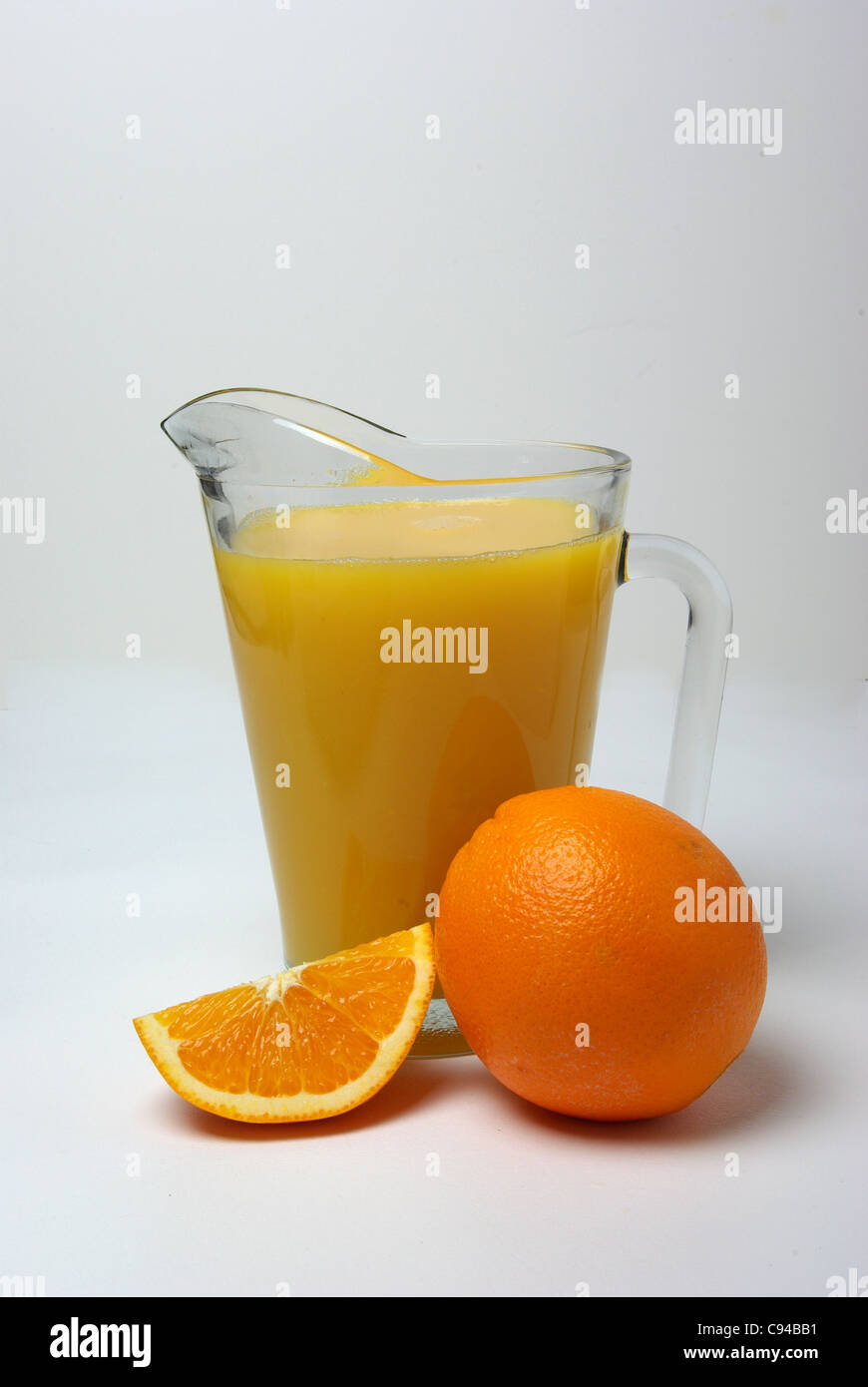 Una brocca di succo di arancia si siede accanto a un arancione e una fettina di arancio. Foto Stock