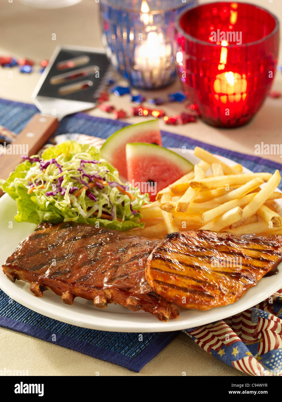 Barbecue costolette di maiale e di pollo serviti con coleslaw, patatine fritte e cocomero in un quarto di luglio impostazione Foto Stock