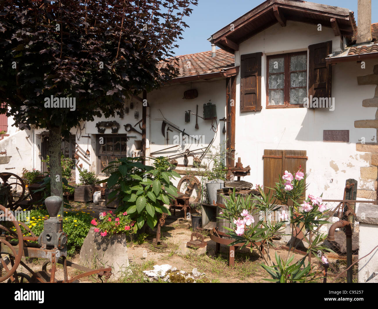 Ascain, villaggio Basco nelle colline ai piedi dei Pirenei, Francia: cottage tradizionale con antichi strumenti sulla parete e in giardino Foto Stock