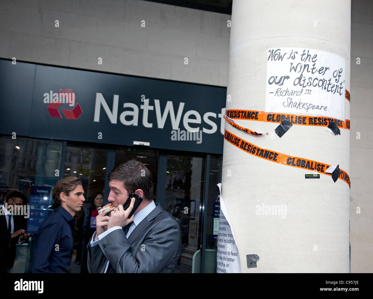 Occupare Londra anti-capitalismo protesta camp fuori dalla cattedrale di St Paul, Londra - uomini d'affari al di fuori di una banca con poster Foto Stock