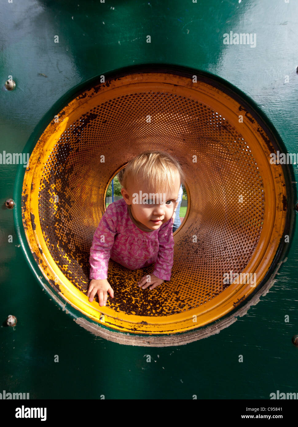 Bambina strisciando attraverso un tunnel di arrampicata Foto Stock