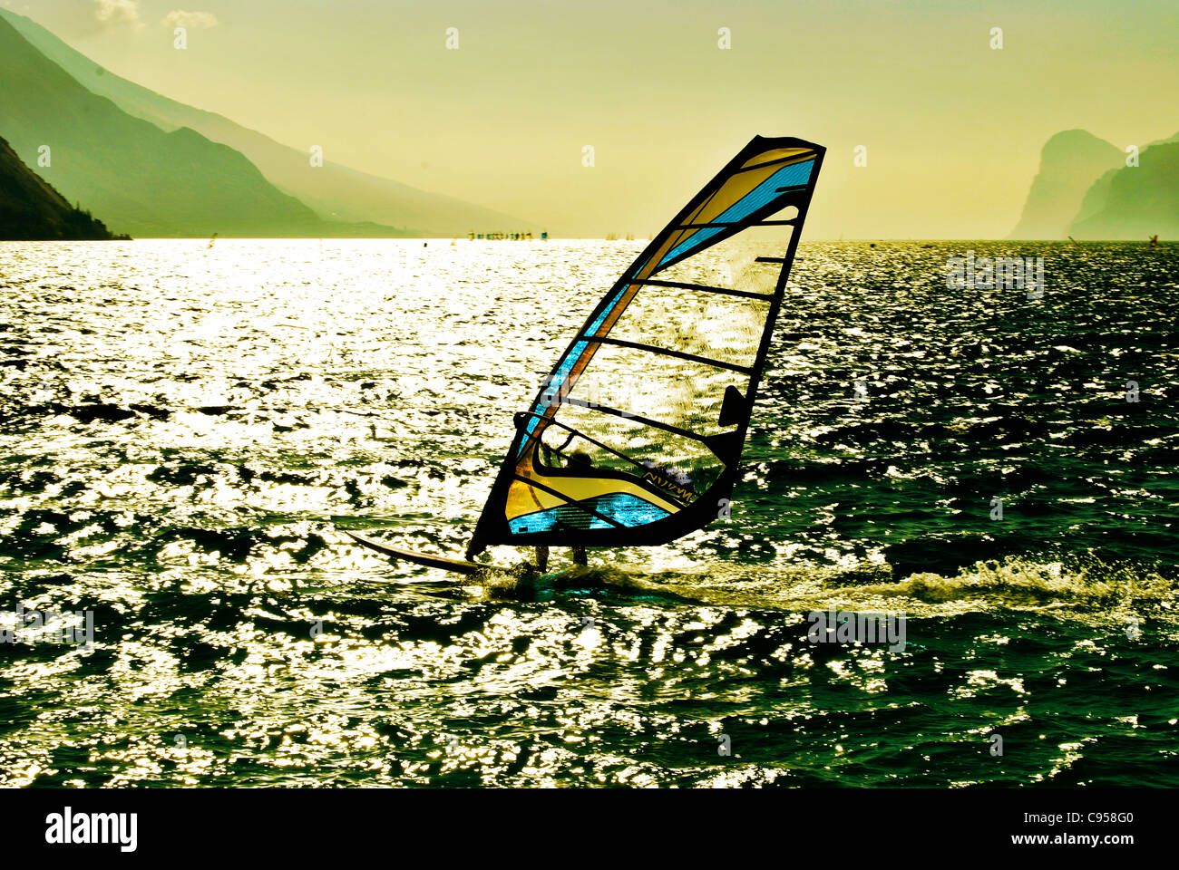 Windsurf panorama silhouette contro una scintillante del lago di Garda in Trentino. Italia Foto Stock