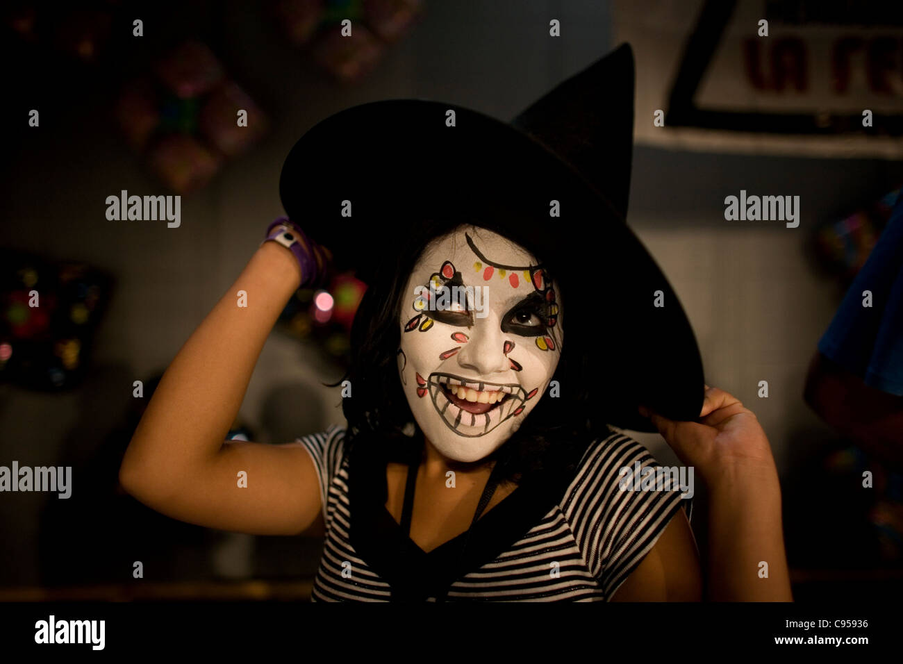 Una ragazza con il volto dipinto e una strega hat sorrisi e possiedono durante il XVI International Clown convenzione di Città del Messico Foto Stock