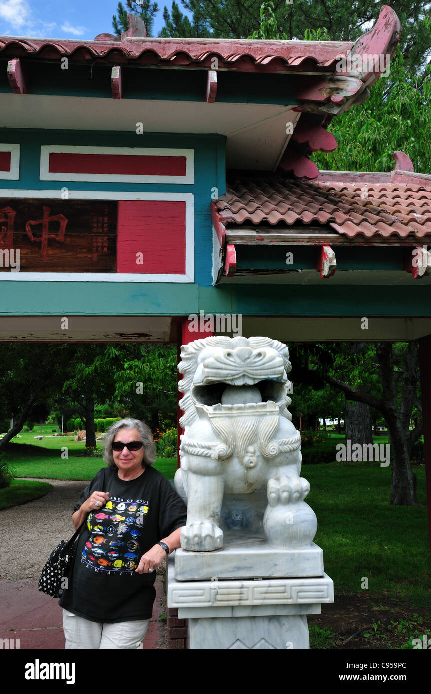 Una donna che si erge da un Leone cinese all'ingresso del giardino cinese presso l'International Peace Gardens in Salt Lake City Foto Stock