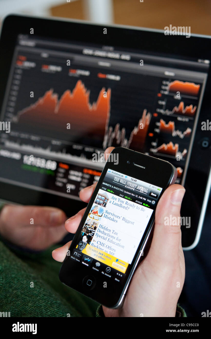 Donna che utilizza computer tablet iPad e iPhone per verificare le scorte i prezzi di mercato del Dow Jones Industrial Average index Foto Stock