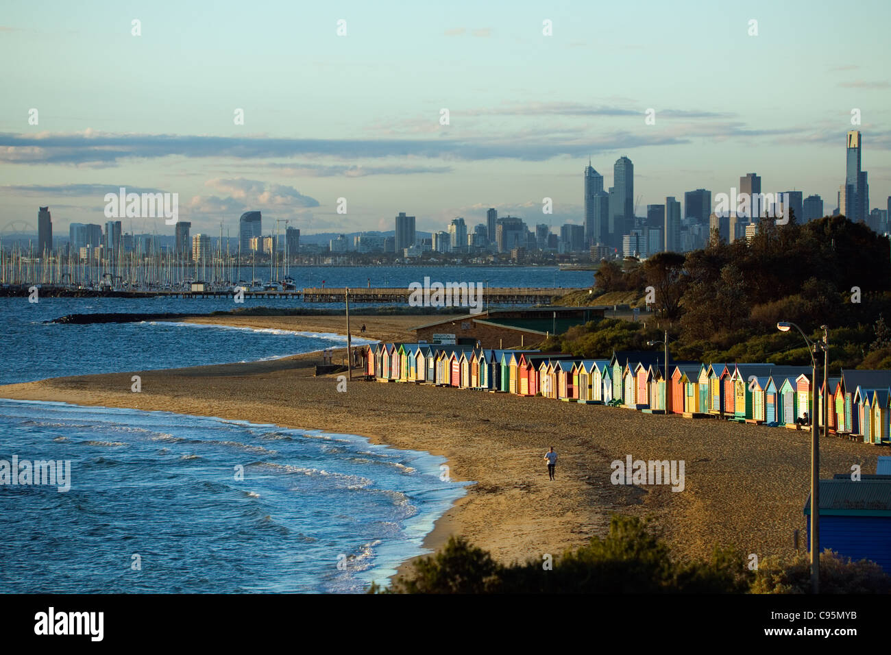 Vista della spiaggia di capanne presso la spiaggia di Brighton con lo skyline della città in background. Melbourne, Victoria, Australia Foto Stock