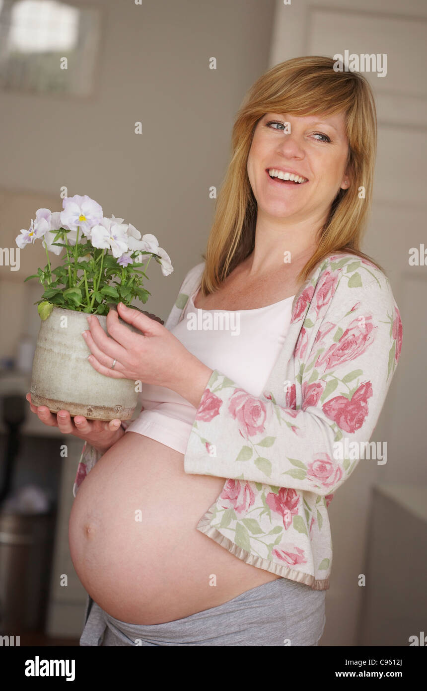 Donna incinta con una pianta in vaso. Ella è di 35 settimane di gravidanza. Foto Stock