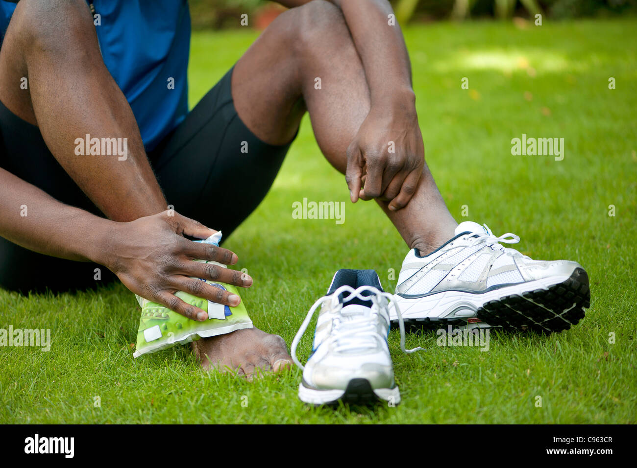 L'uomo applicando una confezione di ghiaccio per la sua caviglia infortunata. Foto Stock