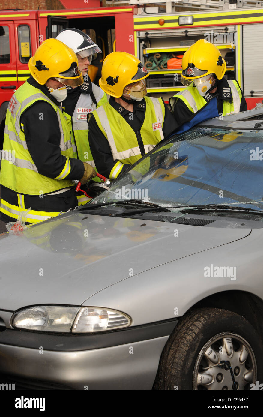 Servizio antincendio ufficiali preparare per il taglio di una vittima di collisione libera da una vettura a seguito di una collisione. Regno Unito Dicembre 2010. Foto Stock