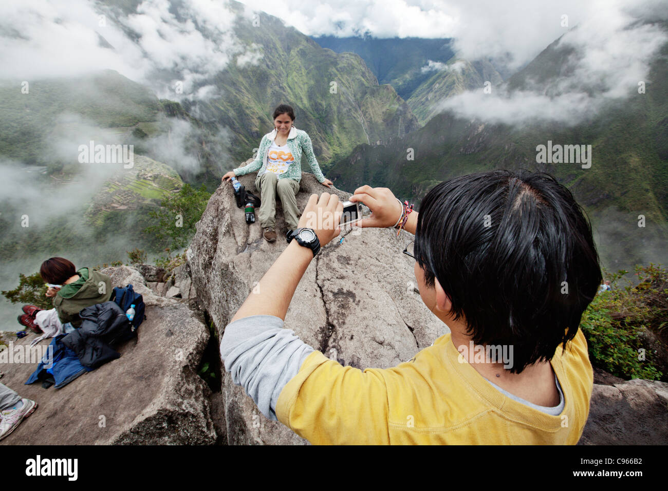I turisti per scattare delle foto su Wayna Picchu montagna. Sullo sfondo il Machu Picchu, il più noto sito turistico nelle montagne delle Ande. Foto Stock