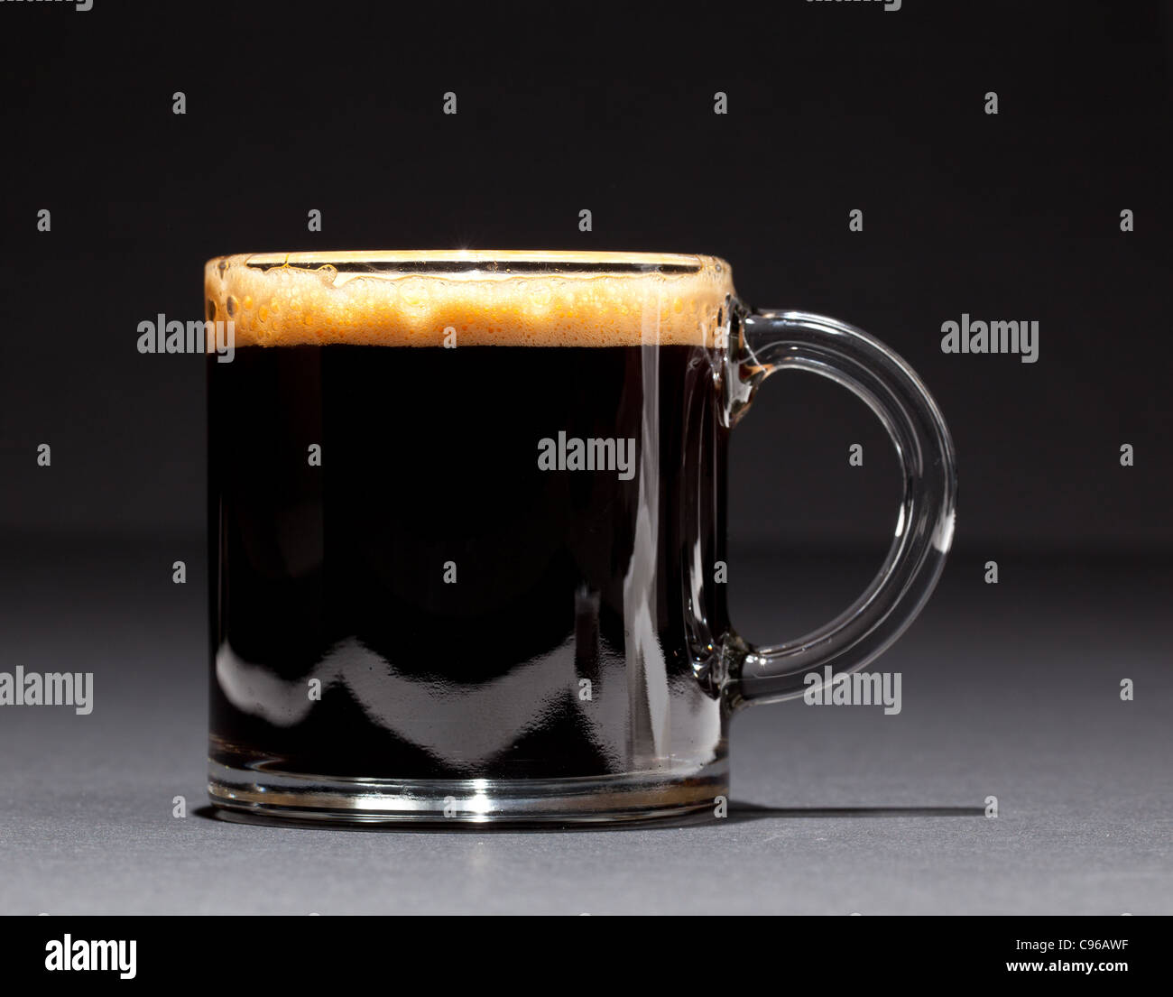 Nero caffè espresso con inebriante della schiuma in un bicchiere di tazza o tazza alta Foto Stock