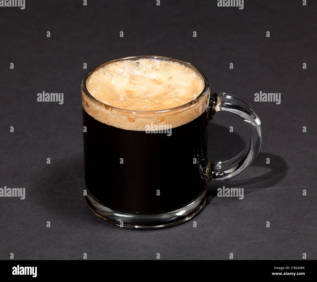 Nero caffè espresso con inebriante della schiuma in un bicchiere di tazza o tazza alta Foto Stock