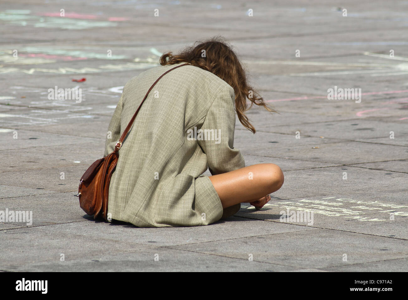 Giovane donna scrivendo su un marciapiede. Alexanderplatz di Berlino, Germania. Foto Stock