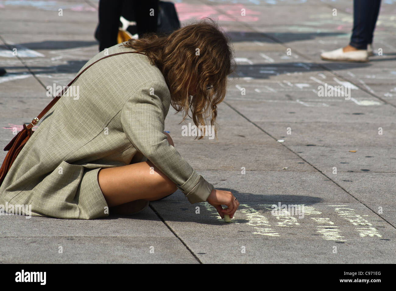 Giovane donna scrivendo su un marciapiede. Alexanderplatz di Berlino, Germania. Foto Stock