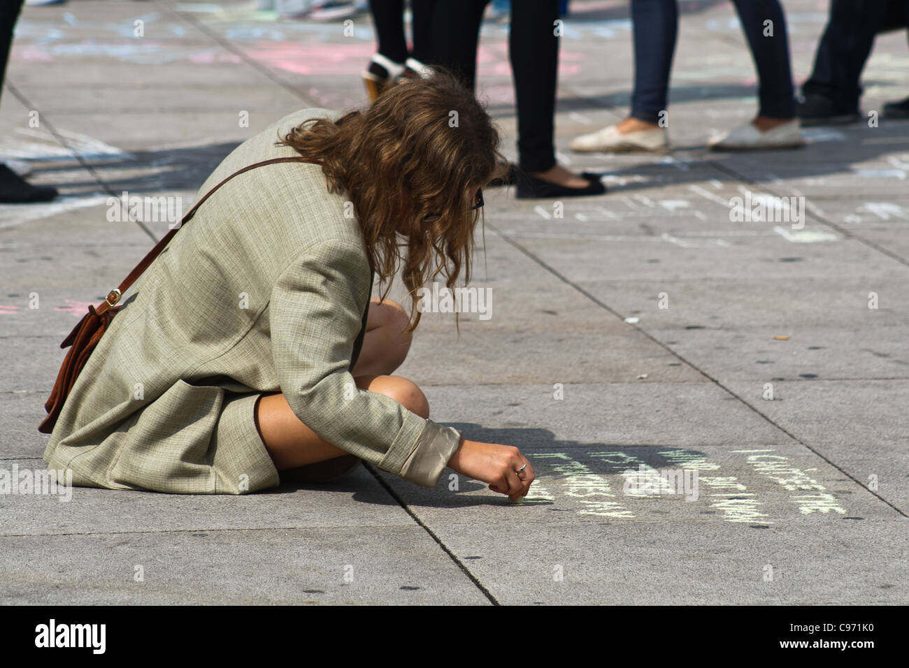 Giovane donna scrivendo su un marciapiede. Alexanderplatz di Berlino, Germania. Foto Stock