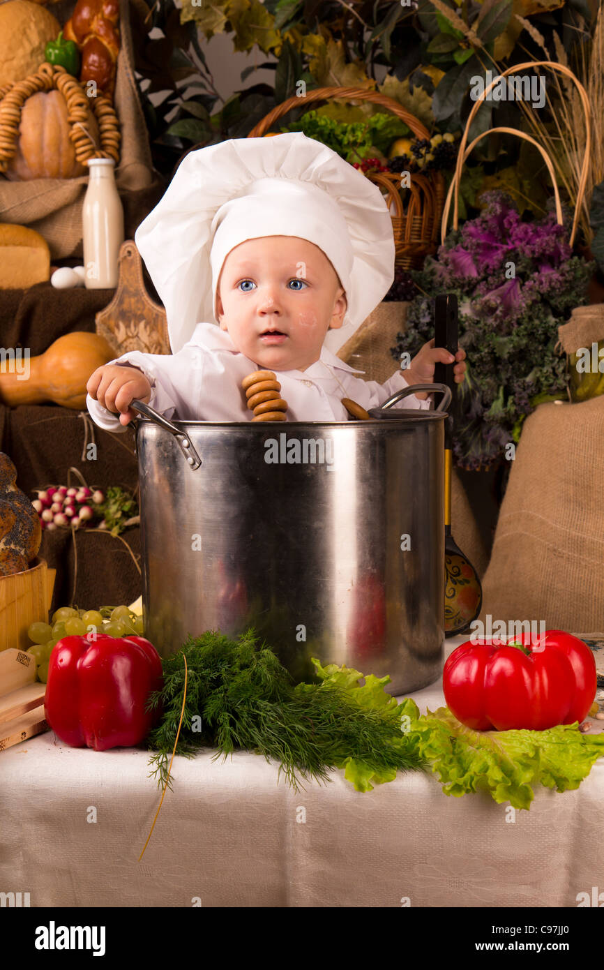 Il bambino che indossa un cappello chef seduti all'interno di una cucina  grande pentola Foto stock - Alamy