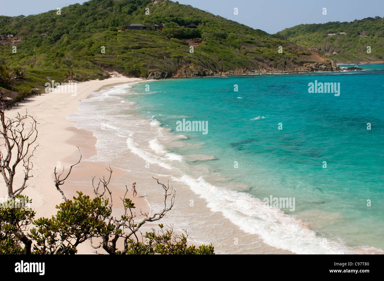 Isole dei Caraibi. Saint Vincent e Grenadine. Mustique. Donna solitaria su maccheroni deserta spiaggia. Foto Stock